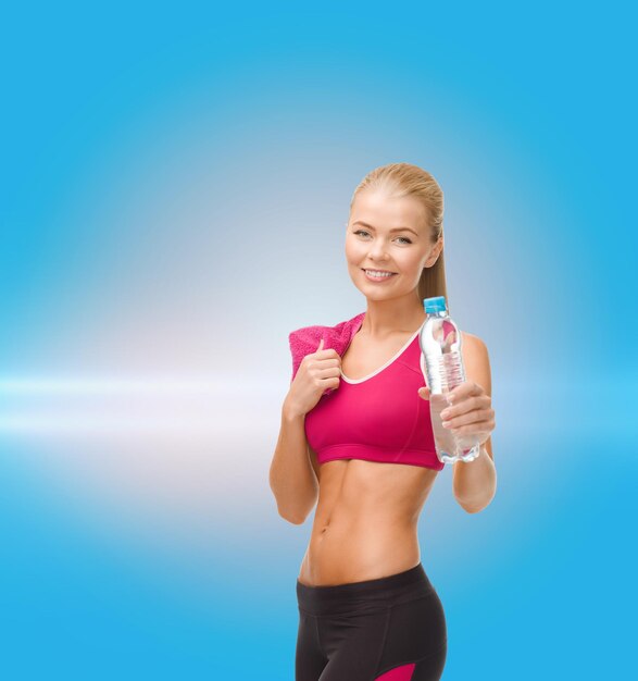 fitness, healthcare and dieting concept - smiling sporty woman with bottle of water and towel