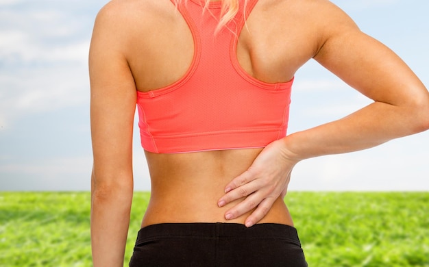 fitness, healthcare and medicine concept - close up of sporty woman touching her back