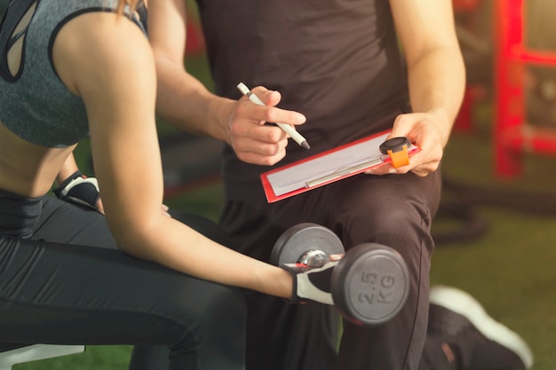 Foto fitness e concetto sano. allenamento sportivo della donna con la testa di legno con l'istruttore che controlla dentro g