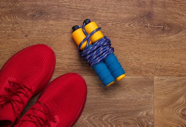 Фото Фитнес, концепция здорового образа жизни. красные кроссовки, скакалка на полу. вид сверху