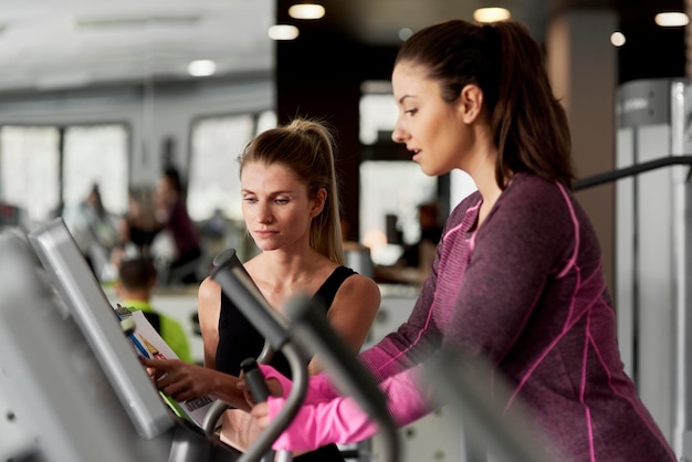 Fitness instructeur die een vrouw helpt bij het sporten in de sportschool