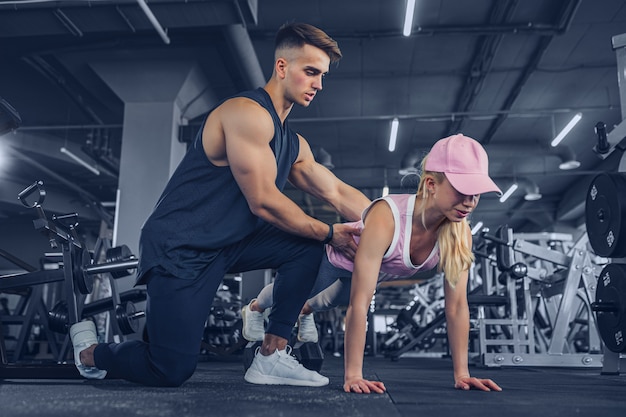 Fitness instructeur helpen meisje om push-ups te doen op training in het fitnesscentrum