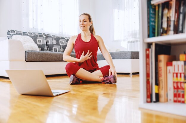 Istruttore di fitness seduto per terra a casa e spiegando gli esercizi allo studente