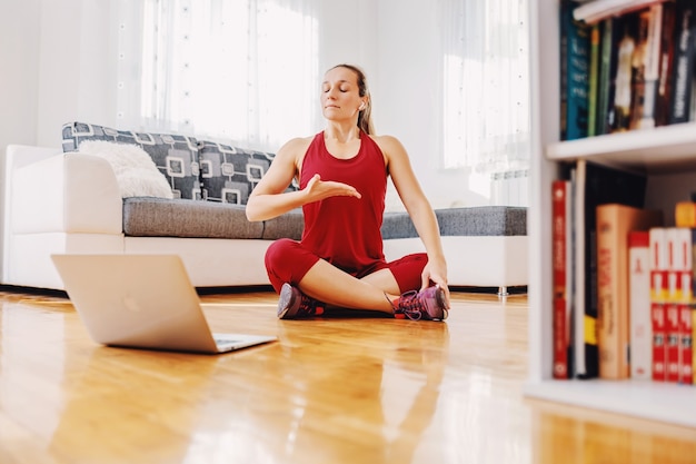 Fitness instructor sitting on the floor at home and explaining exercises to the student