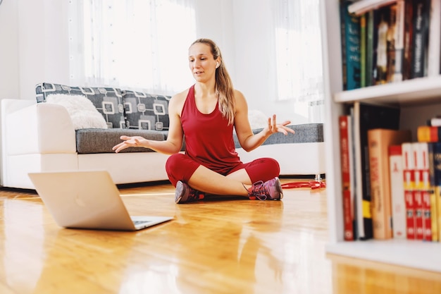 Fitness instructor sitting on the floor at home and explaining exercises to the student