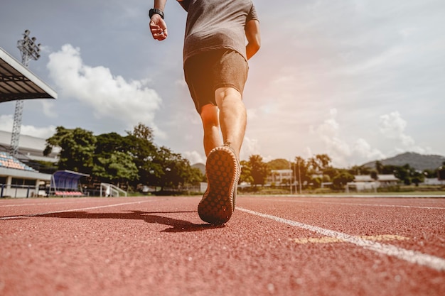 Fitness, jogging, corsa, esercizio fisico, stile di vita e concetto sano. il giovane ha indossato tutte le parti del suo corpo per prepararsi a fare jogging sulla pista di atletica intorno al campo di calcio.