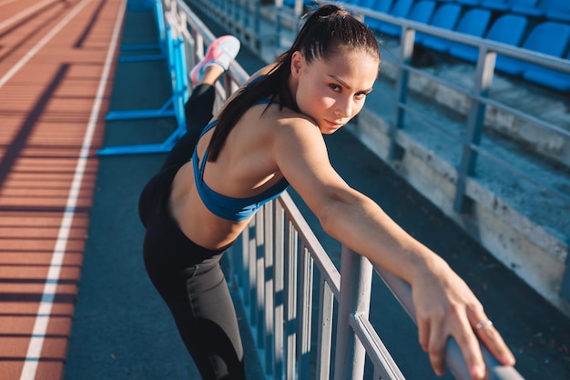 Fitness jonge vrouw die zich uitstrekt voordat ze joggen in het stadion Atletische vrouwelijke stretch na training buiten Sport en mensen concept