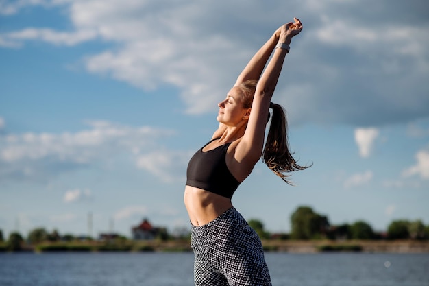 Fitness lady in sportswear doing exercises on pier