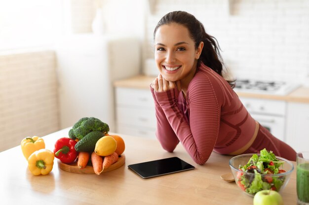 Foto signora fitness navigazione in rete ricette sane sulla tavoletta digitale in cucina