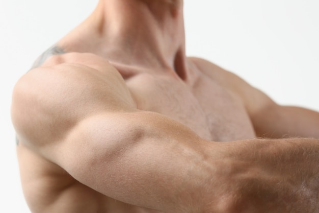 Фитнес мужчина фон плеча бицепс грудных мышц трицепс культурист на сером фоне демонстрирует физическую форму для занятий в тренажерном зале