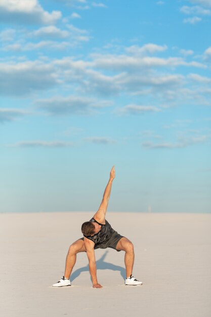 Fitness man doing exercises in sand desert. Sport concept.