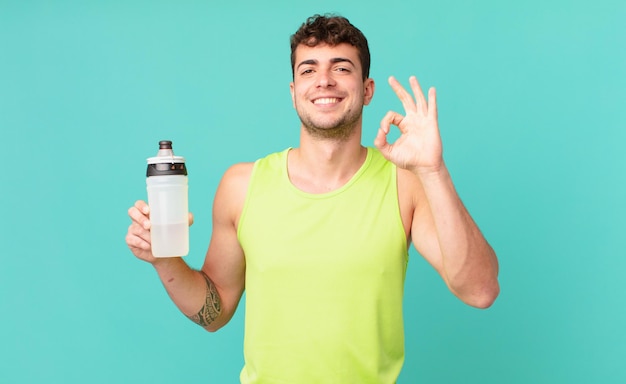 Fitness man feeling happy, relaxed and satisfied, showing approval with okay gesture, smiling