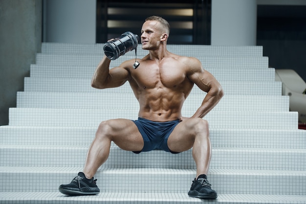 Fitness man in gym drinking water after workout