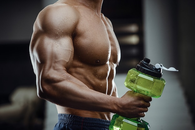 Fitness man in gym drinking water after workout