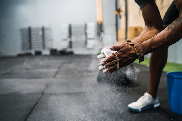 Fitness man handen wrijven met krijt magnesiumpoeder.