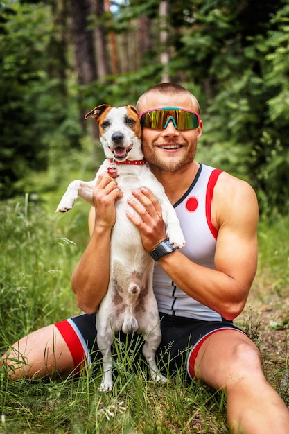 Fitness man in sportkleding met zijn hond in het bos.