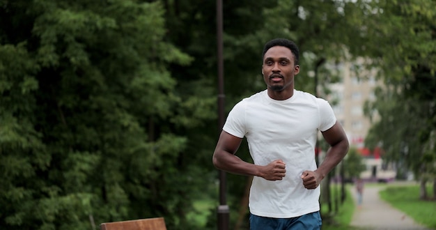 공원 거리에서 야외에서 실행 하는 피트 니스 남자. 운동복을 입고 아침에 공원에서 뛰는 젊은 흑인. 건강한 라이프 스타일 개념입니다.