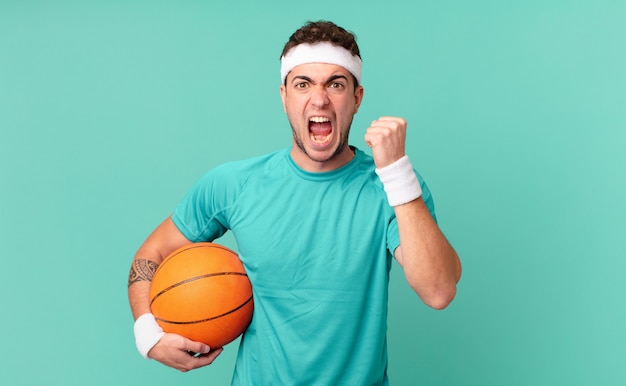 fitness man shouting aggressively with an angry expression or with fists clenched celebrating success