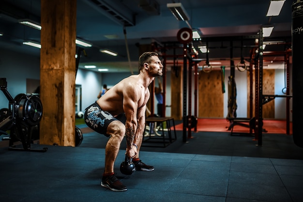 Fitness man swinging kettlebells at the gym