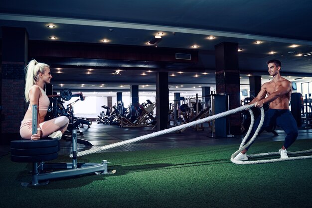 Fitness man working out with battle ropes at gym.