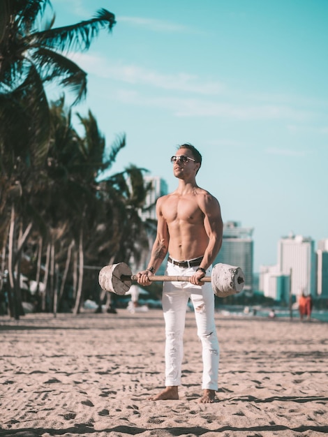 Fitness mannelijk model aan het trainen op het strand