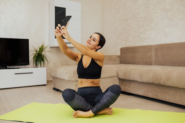 Fitness meisje doet selfie na thuis training. Vrouwelijke atleet ontspannen na training.