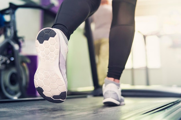 Fitness meisje loopt op loopband vrouw met gespierde benen in moderne sportschool een meisje in witte sneakers loopt op een loopband in de sportschool