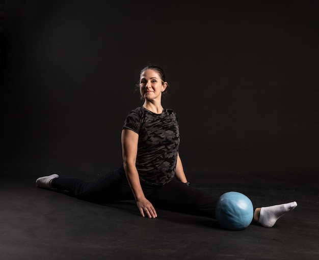 Fitness meisje met Aqua-bal die oefeningen doet voor sport op een zwarte achtergrond die naar de camera kijkt