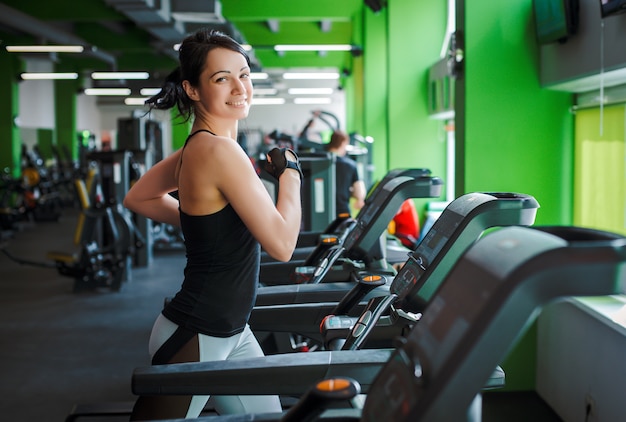 Fitness meisje mooie brunette draait op de loopband ochtend. concept van een gezonde levensstijl.