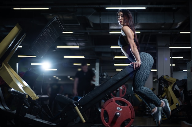 Fitness meisje poseren in de sportschool, pronken met haar lichaam en ontspannen na een training