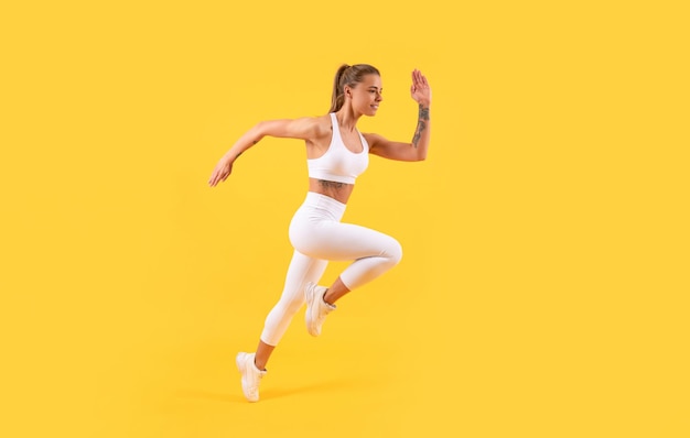 Fitness meisje runner uitgevoerd in sportkleding op gele achtergrond