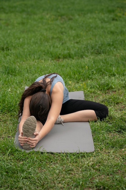 Fitness meisje zittend op het gazon in de tuin van haar huis accijnzen doen