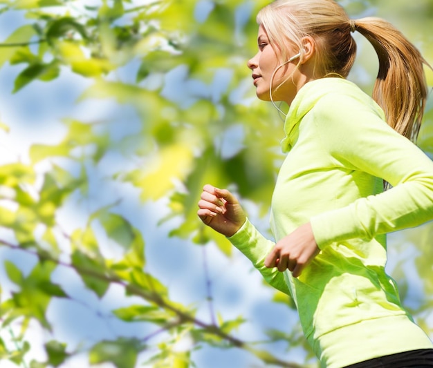 fitness, mensen en een gezond levensstijlconcept - gelukkige jonge vrouwelijke hardloper die buiten jogt