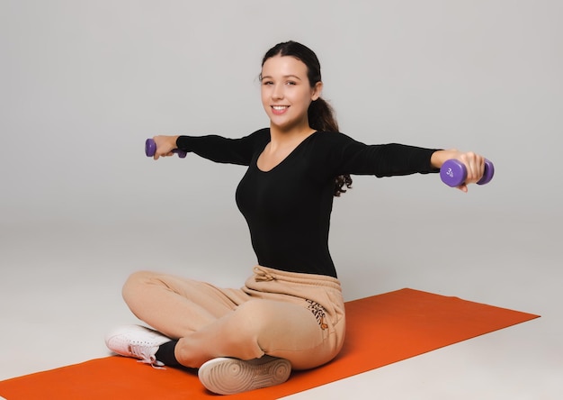 Fitness model exercises with dumbbells and drinks water from a sports bottle