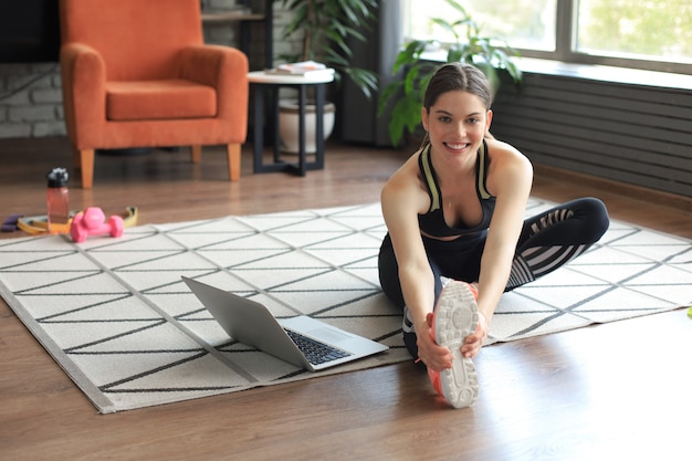 Fitness mooie slanke vrouw doet fitness rekoefeningen thuis in de woonkamer. Blijf thuis activiteiten. Sporten, gezonde levensstijl.