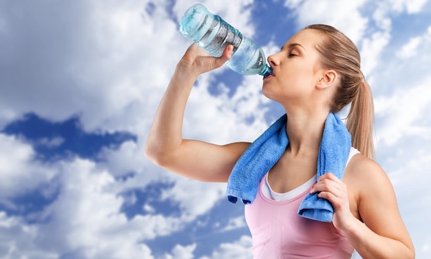 Fitness mooie vrouw drinkwater en zweten na het sporten op een warme zomerdag op het strand.