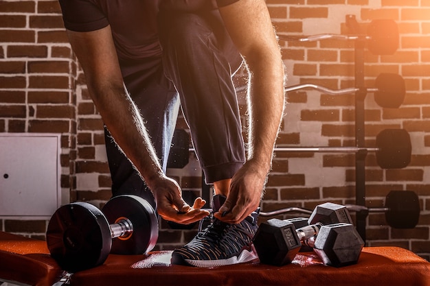 Fitness motivation and muscle training concept. man in sneakers
tying shoelaces in sunlight.