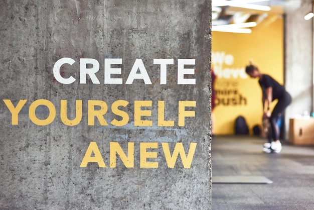 Foto citazione di motivazione per il fitness crea te stesso di nuovo scritto sul muro di cemento grigio in palestra, le persone che lavorano