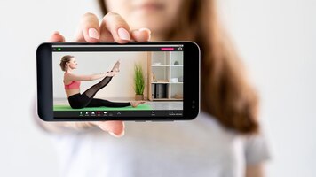 Фото Фитнес онлайн виртуальный тренажерный зал домашняя тренировка девушка показывает спортивную женщину, выполняющую упражнения на растяжку на экране смартфона, изолированном на светлом размытом фоне