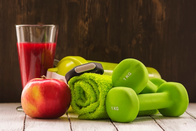 Фото Концепция фитнеса или диеты: гантели, свежий красный коктейль, яблоко