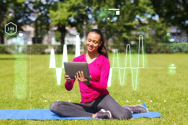 Photo fitness, park, technology and sport concept - smiling african american woman with tablet pc computer sitting on mat outdoors