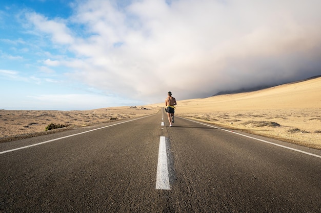 Persona di forma fisica che corre sulla strada attraverso il deserto