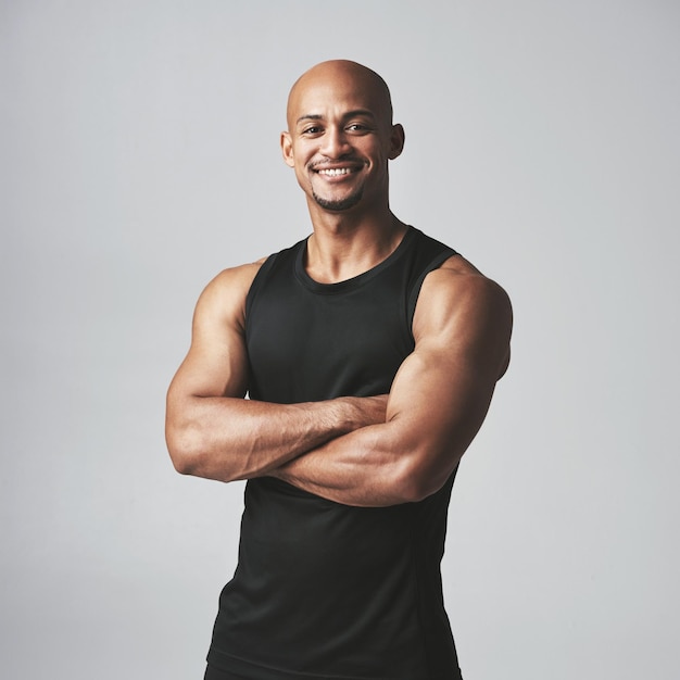 Fitness portret gelukkige man en armen gekruist geïsoleerd op studio achtergrond gezond lichaam of spiertraining Glimlach op gezicht van sterke atleet VS bodybuilder of Afrikaanse persoon oefening of sportkracht