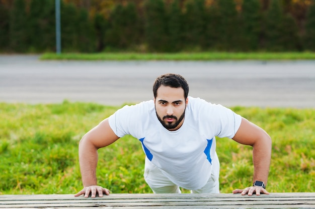 Fitness. Push-up exercise fitness man training arms muscles at outdoor gym