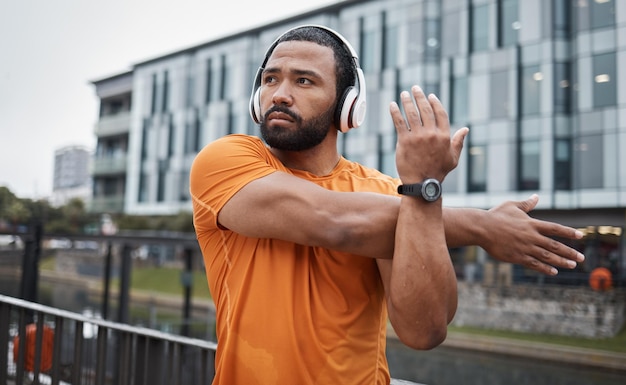 Fitness runner or black man stretching in city for running training cardio exercise or workout start in London Wellness mindset or healthy sports athlete in headphones streaming radio or podcast