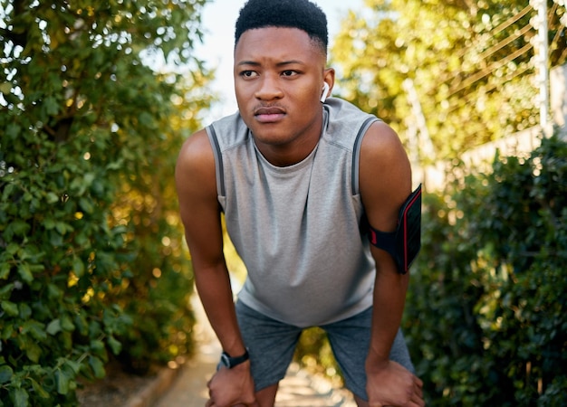 Fitness running and tired with a sports black man outdoor during summer taking a break from a workout Exercise health and exhausted with a male runner or athlete resting while training outside