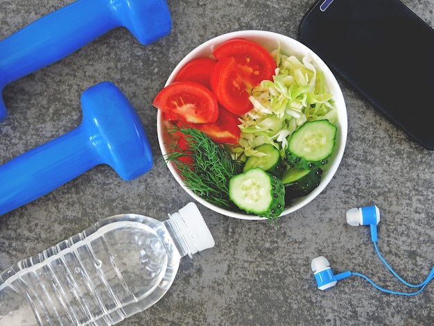 Fitness salad, dumbbells and measuring tape