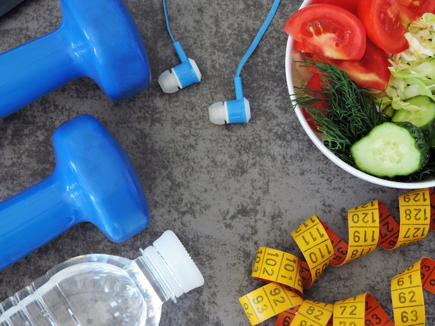 Fitness salad, dumbbells and measuring tape