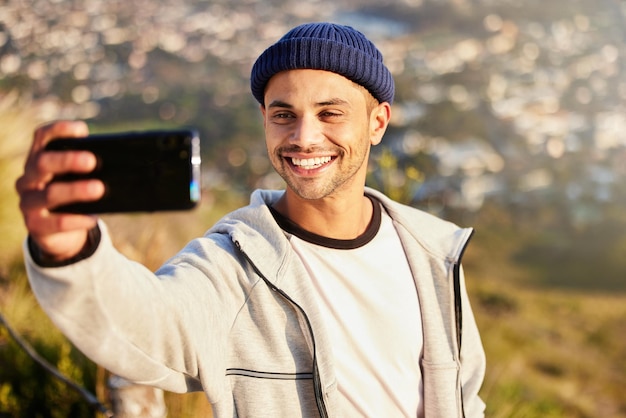 Photo fitness selfie and male hiking on the mountain after walking for a wellness exercise in nature sports health and young man hiker taking a picture while trekking outdoor for a cardio workout
