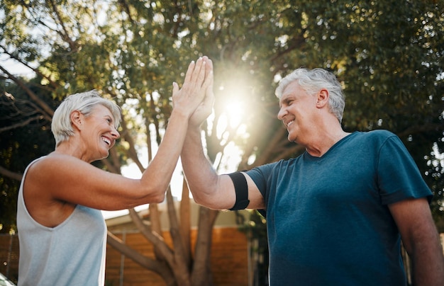 Fitness senior couple high five for support teamwork and exercise motivation with sunshine outdoor exercise and wellness Success achievement or target goal of elderly people for workout results